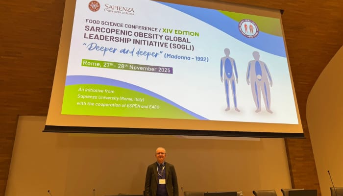 A man stands in front of a large presentation screen at the Sarcopenic Obesity Global Leadership Initiative conference in Rome, dated November 27-28, 2025.