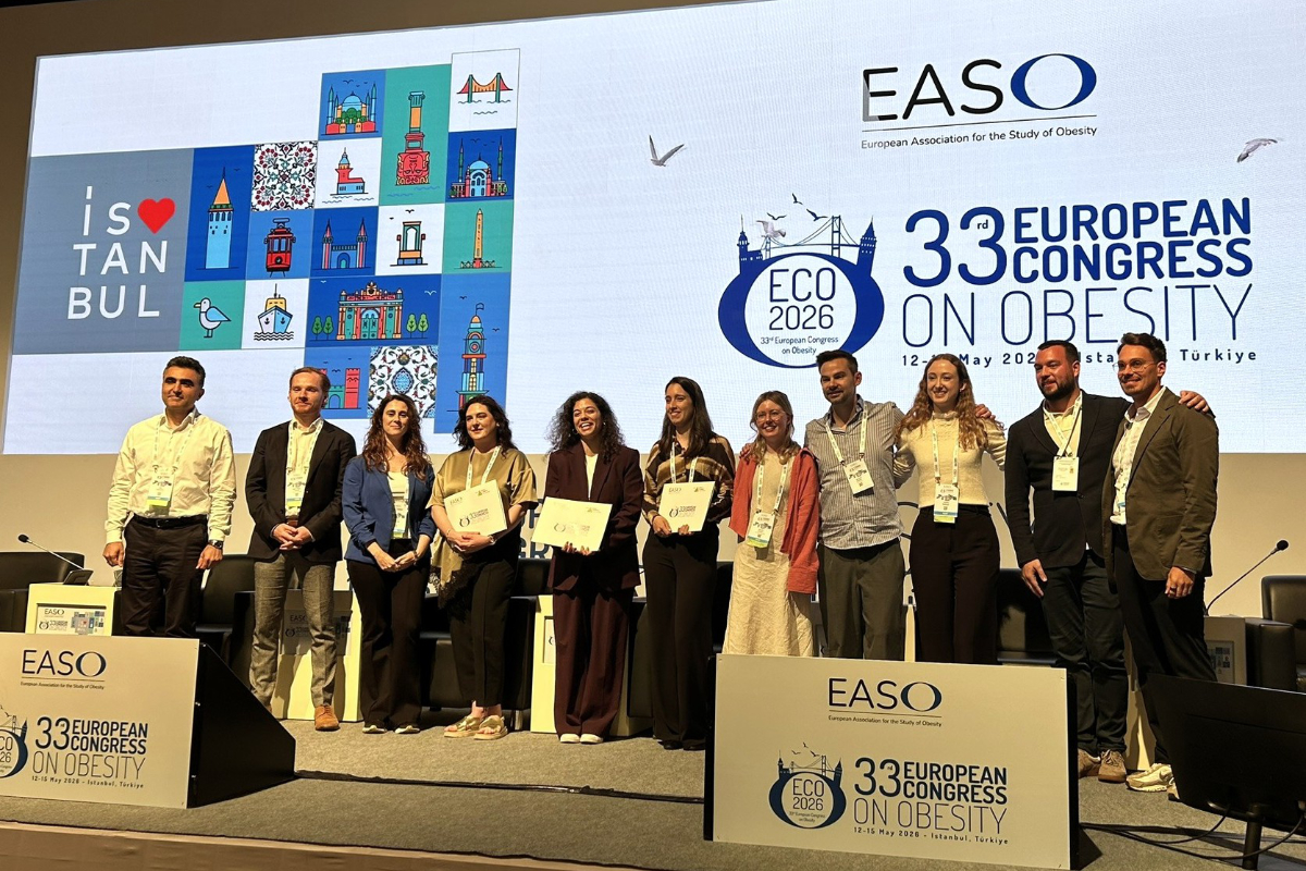 A group of people stand on stage holding certificates at the 33rd European Congress on Obesity, with event banners and a screen in the background.